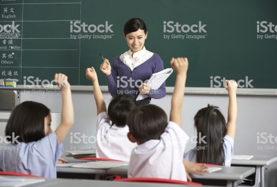 Students In A chinese School Classroom Putting Up Their Hands To Answer The Teacher