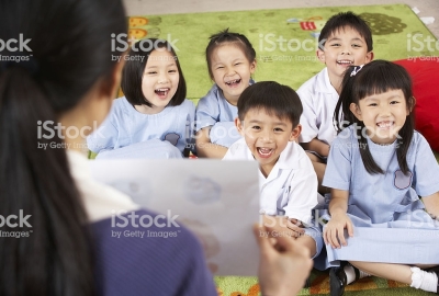 Teacher Showing Painting To Students In Chinese School Classroom Sitting Down Smiling